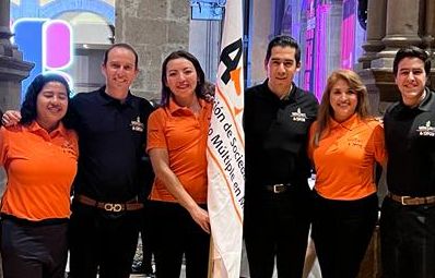 Grupo de participantes junto a la bandera de ASOFOM en un evento institucional